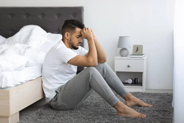 Életgondok. Depressziós Pensive fiatal arab férfi ül a padlón az ágy mellett — Stock Fotó