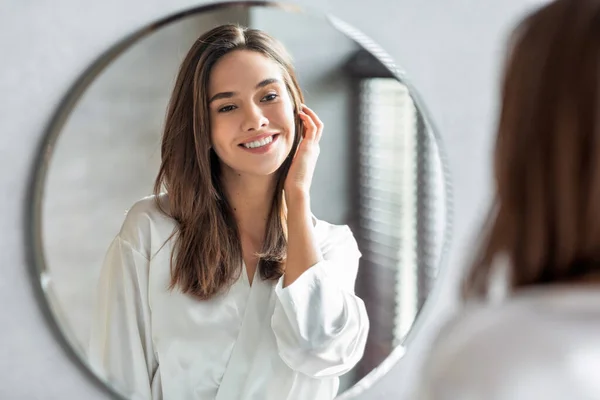 Koncepcja piękna. Portret atrakcyjnej szczęśliwej kobiety patrzącej na lustro w łazience — Zdjęcie stockowe