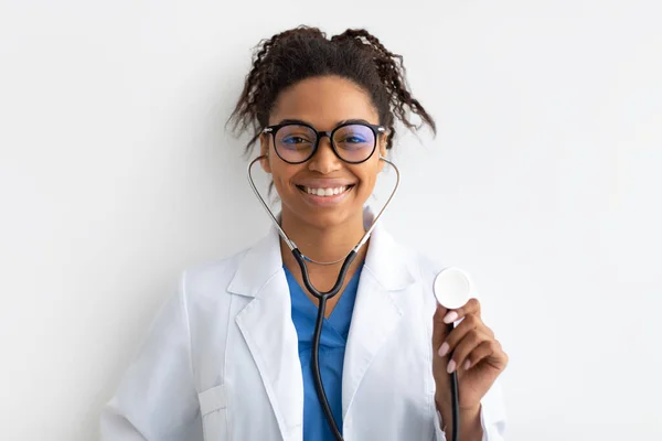 Portré fekete orvos mosolyog és bemutatja sztetoszkóp — Stock Fotó