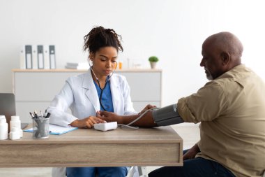 Siyahi kadın doktor hastaların elindeki basıncı kontrol ediyor.