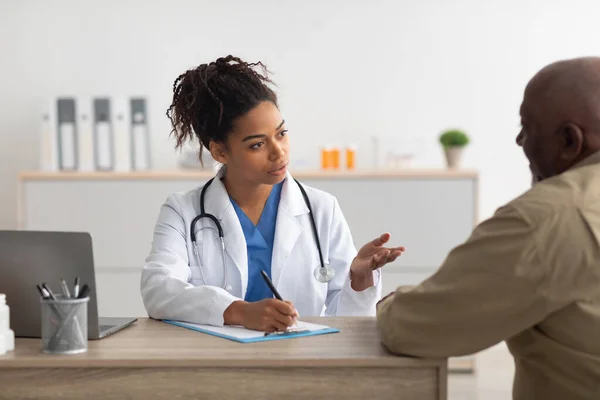 Joven médico negro explicando plan de tratamiento al paciente masculino —  Fotos de Stock