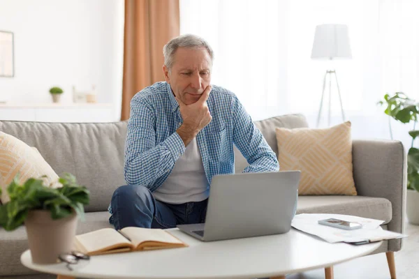 Portrait of pensive mature using laptop at home — Stock Photo, Image