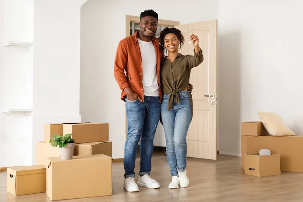 Glädjefyllda svarta par visar nyckel stående i New House — Stockfoto