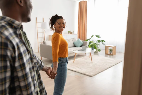 Счастливые афроамериканские супруги входят в дом, держа руки в помещении — стоковое фото