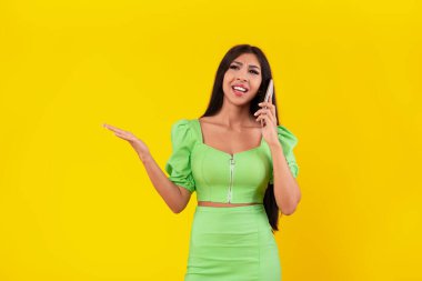 Sinirli kadın sarı stüdyoda cep telefonuyla konuşuyor.