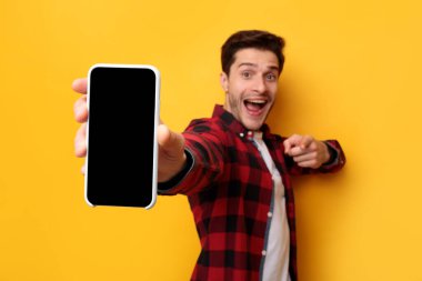 Şok olmuş adam boş akıllı telefon ekranını işaret ediyor.