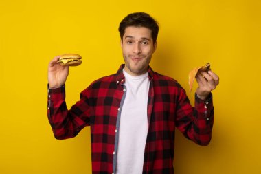 Hamburger ve pizza dilimleri tutan komik adam.