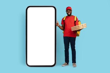 Yakışıklı, kara teslimatçı. Yanında pizza kutuları olan. Yanında boş akıllı çocuk duruyor.