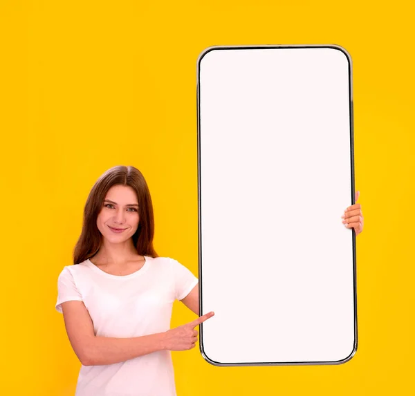 Junge schöne Frau mit leerem Bildschirm hält und zeigt auf Handy — Stockfoto