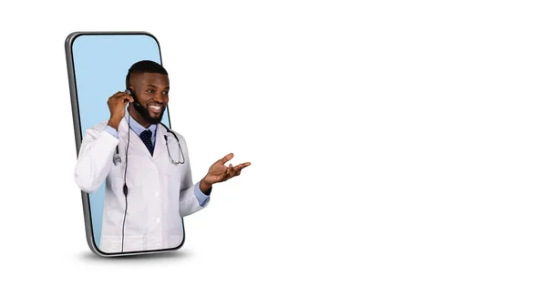Teletıp. Dost canlısı siyah doktor. Kulaklık takıyor. Smartphone Screen 'den dikizliyor. — Stok fotoğraf