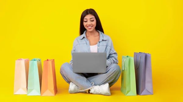 Gelukkige vrouw met boodschappentassen met laptop — Stockfoto