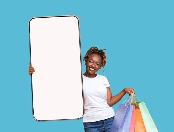 Shopping App. Glad ung svart dam håller tom smartphone och shopper väskor — Stockfoto