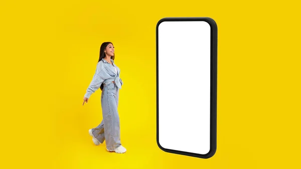 Женщина стоит рядом с большим белым пустым экраном смартфона — стоковое фото