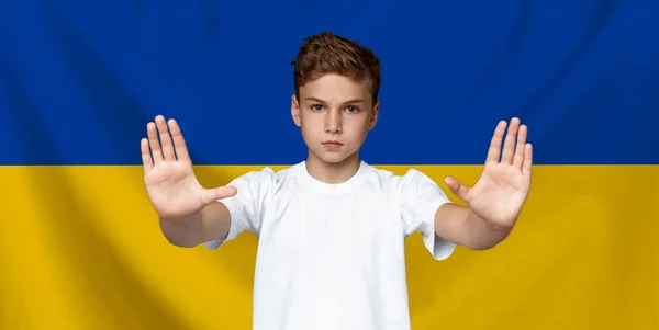 Adolescente menino fazendo parar gesto sobre amarelo azul bandeira ucraniana fundo — Fotografia de Stock