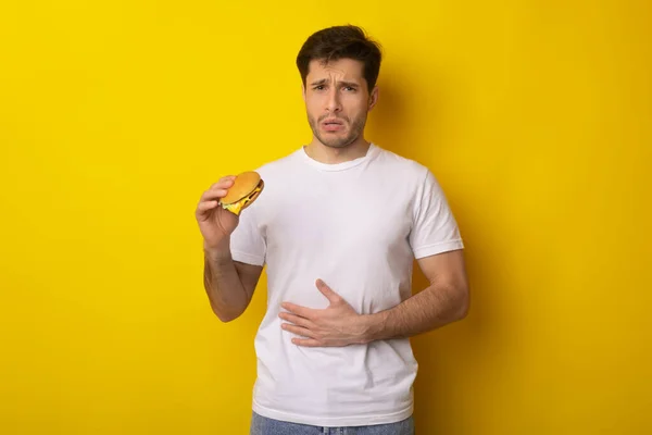 Sad Young Guy Holding Burger Suffering From Stomachache — Stock Photo, Image