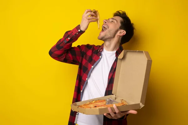 Happy Guy Holding Box mordiendo pizza en el estudio — Foto de Stock