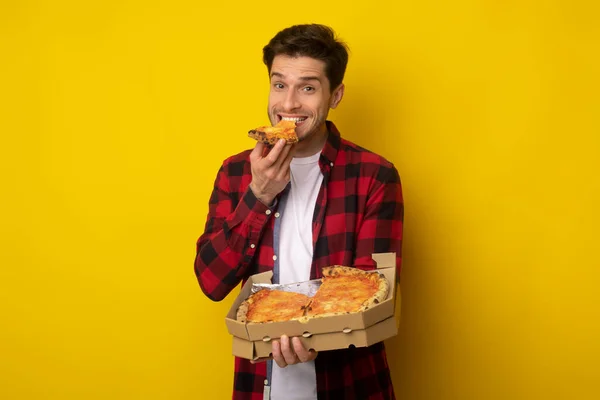 Happy Guy segurando caixa mordendo pizza no estúdio — Fotografia de Stock