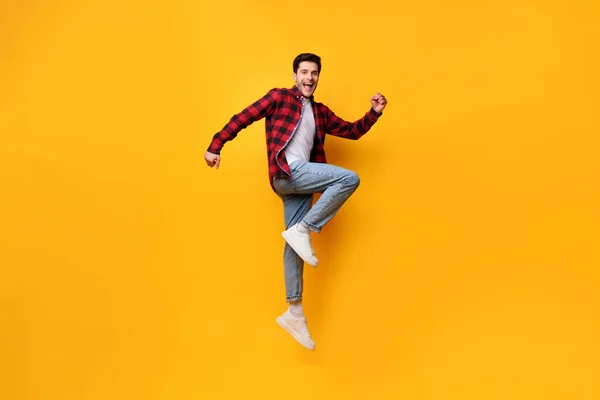 Heyecanlı genç adam turuncu stüdyoda zıplıyor. — Stok fotoğraf