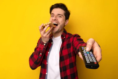 Pizza yiyen ve uzaktan kumandalı televizyon izleyen komik adam.