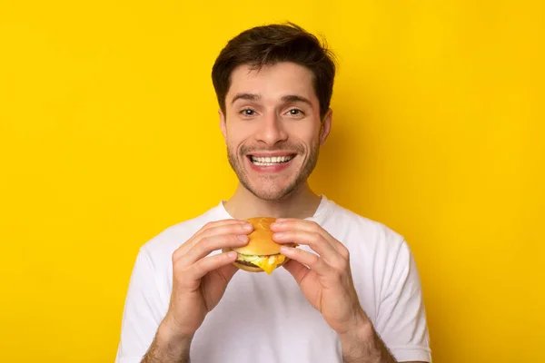 Smiling Young Guy Holding Burger At Studio — Stock Photo, Image