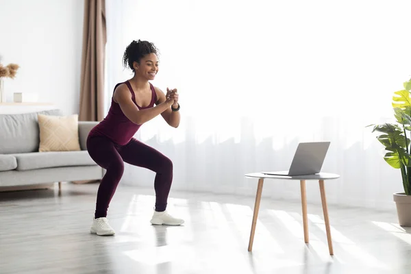 Позитивная черная леди тренируется дома, смотрит онлайн видео — стоковое фото