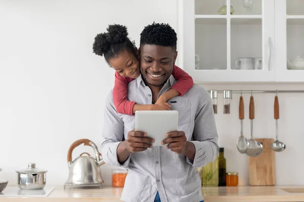 Счастливые чернокожие отец и дочь вместе пользуются планшетом дома — стоковое фото