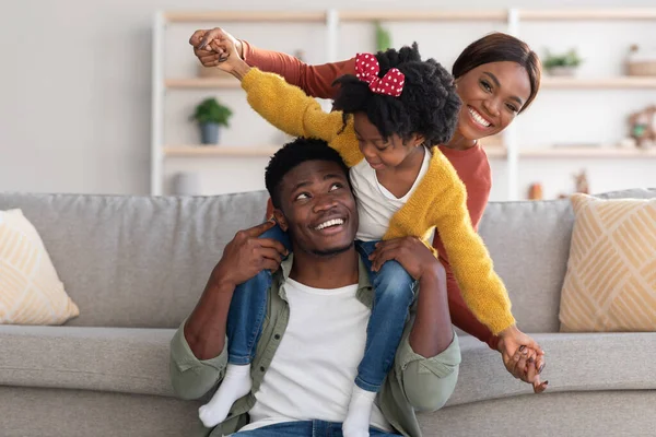 Familia feliz. Padres afroamericanos divirtiéndose con su hija en casa — Foto de Stock