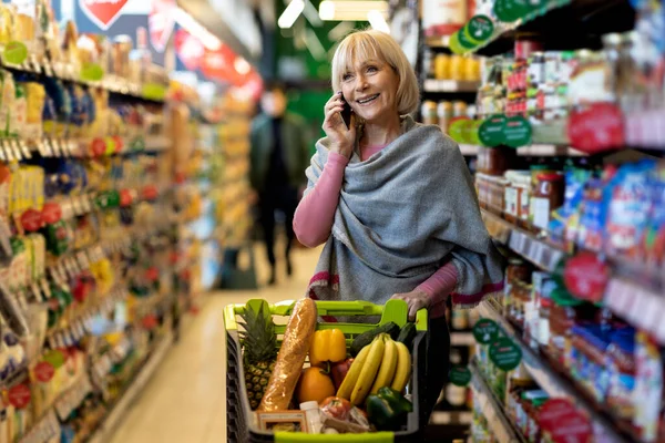 쇼핑하면서 전화 통화를 하는 연로 한 여자 — 스톡 사진