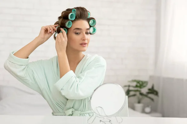 Senhora Curling Cabelo Com Curlers Olhando para o espelho no quarto — Fotografia de Stock