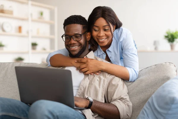 Afrikaans Amerikaans paar zitten op de bank, met behulp van laptop — Stockfoto