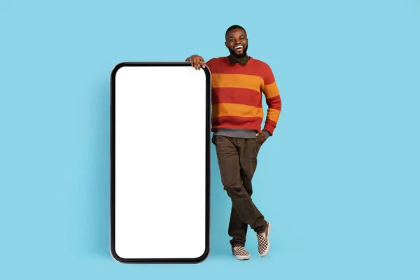 Mobilní Mockup. Šťastný mladý černošky muž se opírá o velký prázdný smartphone — Stock fotografie