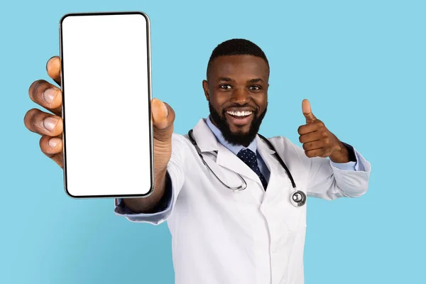 快乐的黑人医生在相机前演示空白智能手机和显示哑铃 — 图库照片