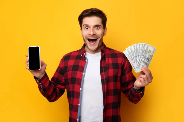 Hombre sosteniendo el dinero y la pantalla grande del teléfono inteligente blanco vacío —  Fotos de Stock