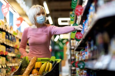 Salgın hastalık varken, süpermarkette maske takan bir büyükanne.