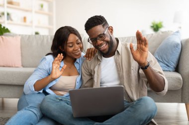 Siyah çift el sallayan dizüstü bilgisayarla video görüşmesi yapıyor.