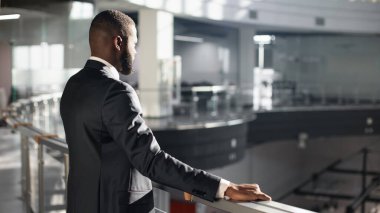 Düşünceli Afrikalı Amerikalı girişimci trabzanların yanında duruyor.