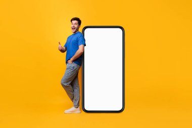 Beyaz, boş, akıllı telefon ekranına yaslanan adam başparmak kaldırıyor.