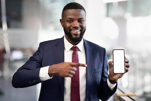 Homme d'affaires noir positif pointant vers le smartphone avec écran vide — Photo