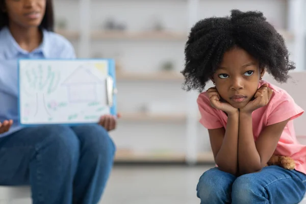 Gelangweiltes kleines Mädchen meidet unkenntliche Kinderpsychologin — Stockfoto