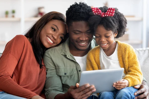 Счастливая семья черный с Preteen дочь расслабляется с цифровой таблетки дома — стоковое фото