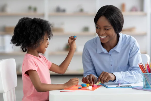 Мила маленька чорна дівчинка і вчителька грають з тістом — стокове фото