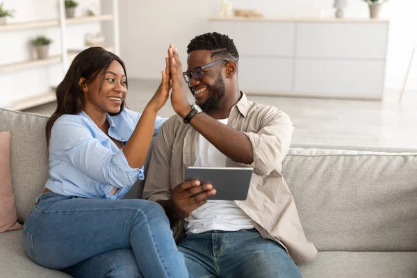 Afrikaans amerikaans paar met behulp van tablet, vieren winnen geven high five — Stockfoto