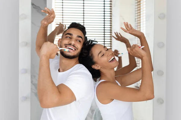 Alegre árabe pareja cantando juntos mientras cepillando dientes en baño —  Fotos de Stock