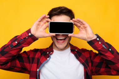 Heyecanlı adam gözlerini boş akıllı telefon ekranıyla kapatıyor.