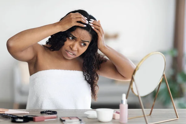 Jovem afro-americana perturbada verificando seu cabelo — Fotografia de Stock