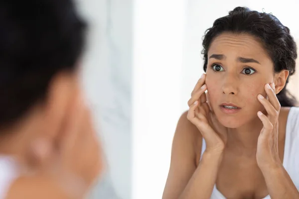 Atopisch huidconcept. Bezorgde jonge vrouw kijken naar spiegel en ontroerende gezicht — Stockfoto