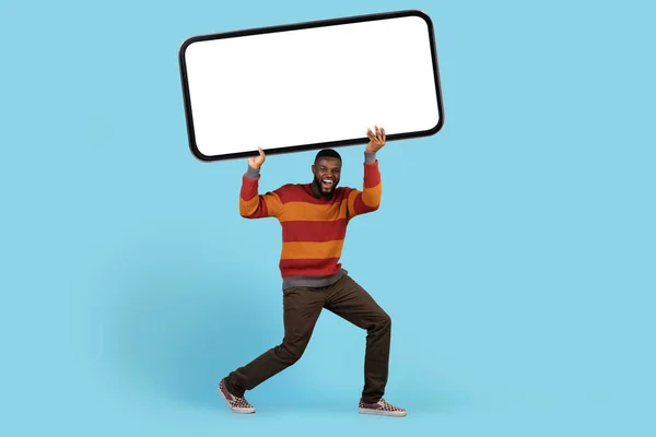 Gek aanbod. Grappige Afro-Amerikaanse man houdt Big Blank Smartphone Boven Hoofd — Stockfoto