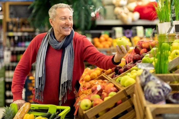 Neşeli yaşlı adam süpermarkette kaliteli ürünlerin tadını çıkarıyor. — Stok fotoğraf