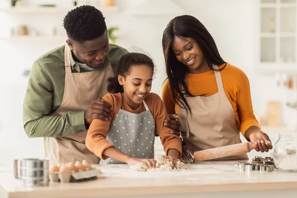 Svart familie som klemmer deig sammen baker kjeks på kjøkkenet – stockfoto
