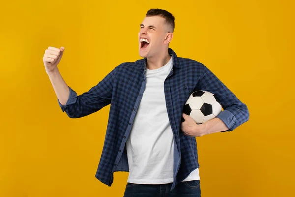 Man schreeuwend gebaren Ja Holding Ball viert overwinning, gele achtergrond — Stockfoto